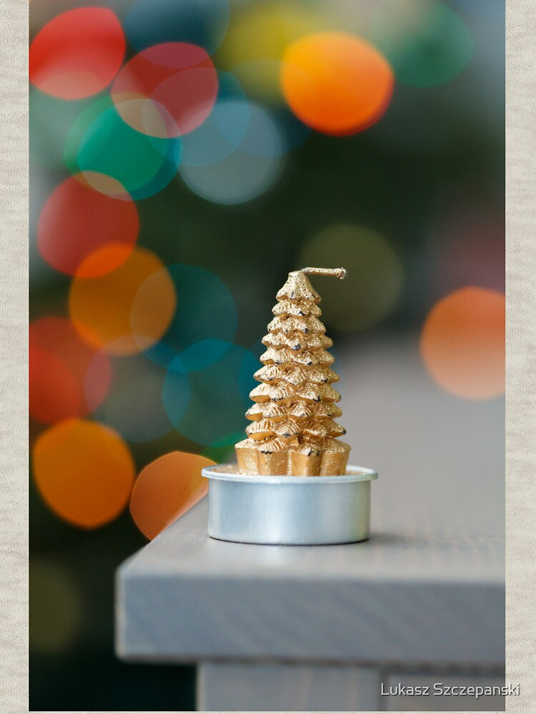 Christmas tree shaped candle on wooden cupboard against christmas lights by Lukasz Szczepanski